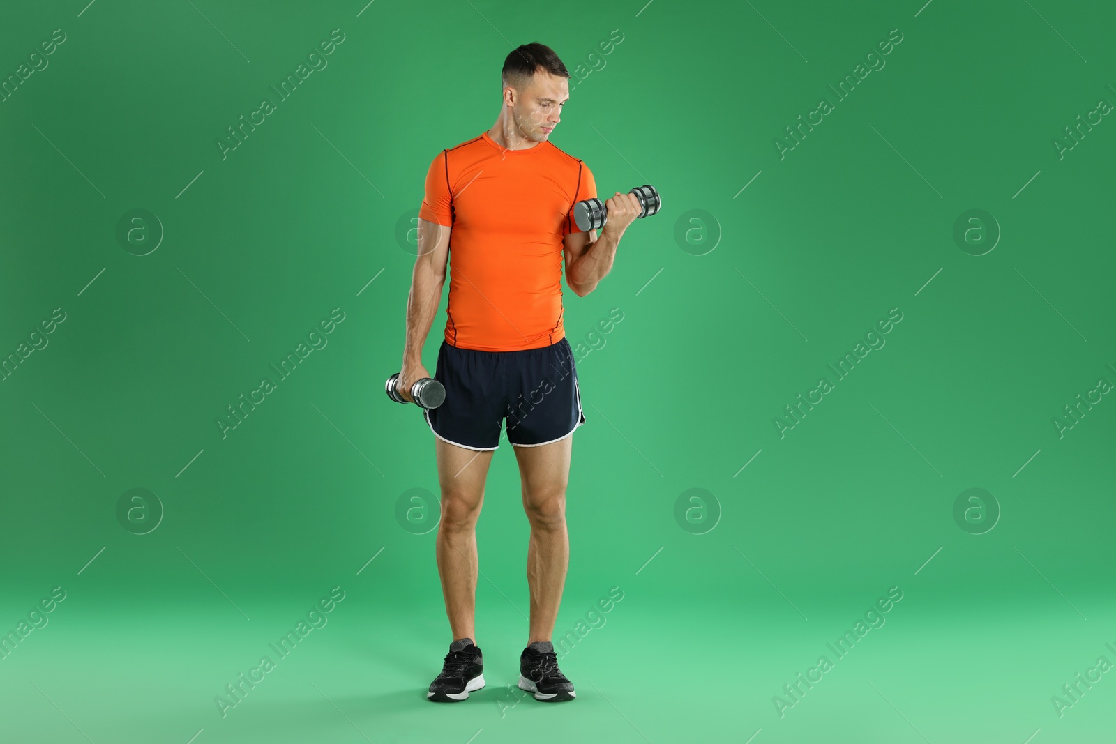 Photo of Man exercising with dumbbells on green background