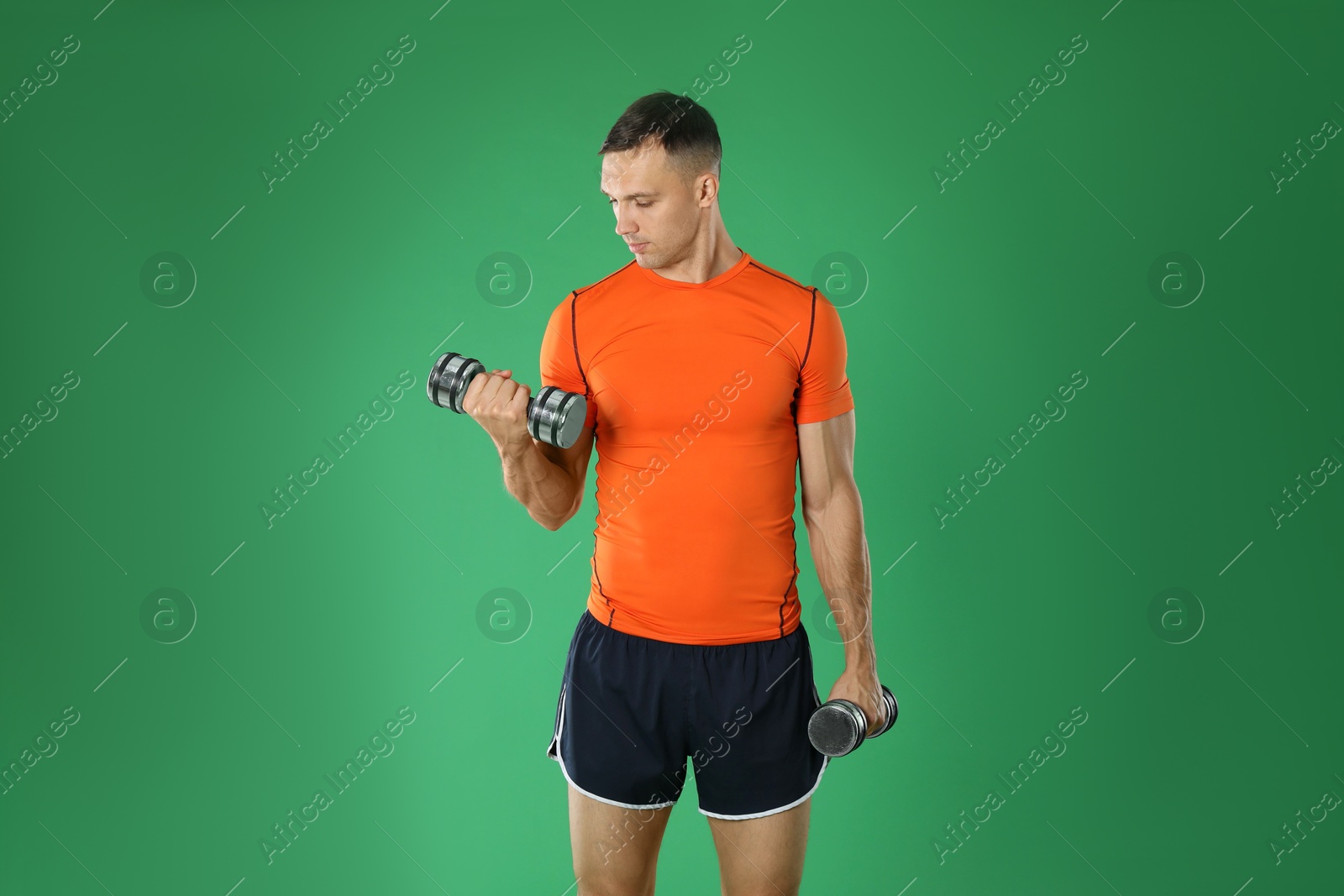 Photo of Man exercising with dumbbells on green background