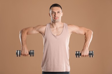 Photo of Man exercising with dumbbells on light brown background