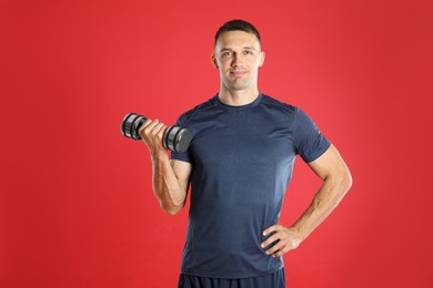 Photo of Man exercising with dumbbell on red background