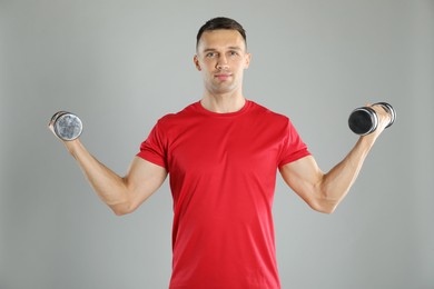 Photo of Man exercising with dumbbells on grey background