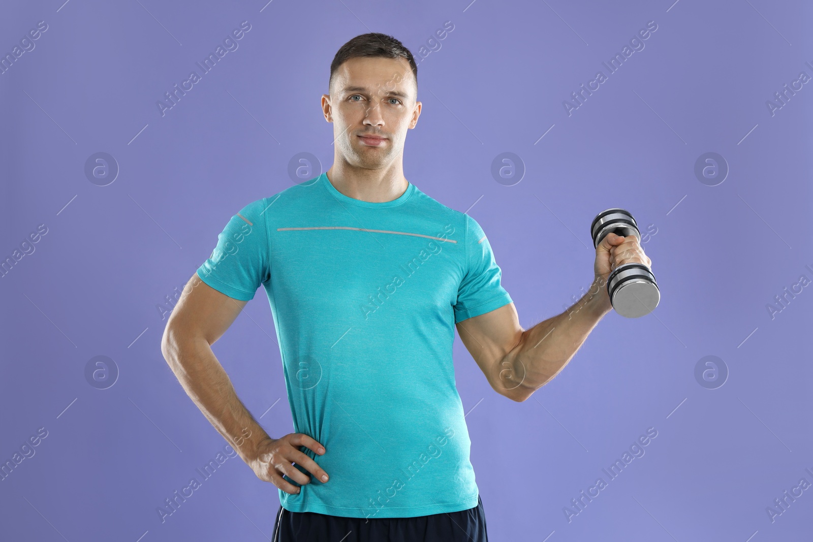 Photo of Man exercising with dumbbell on violet background