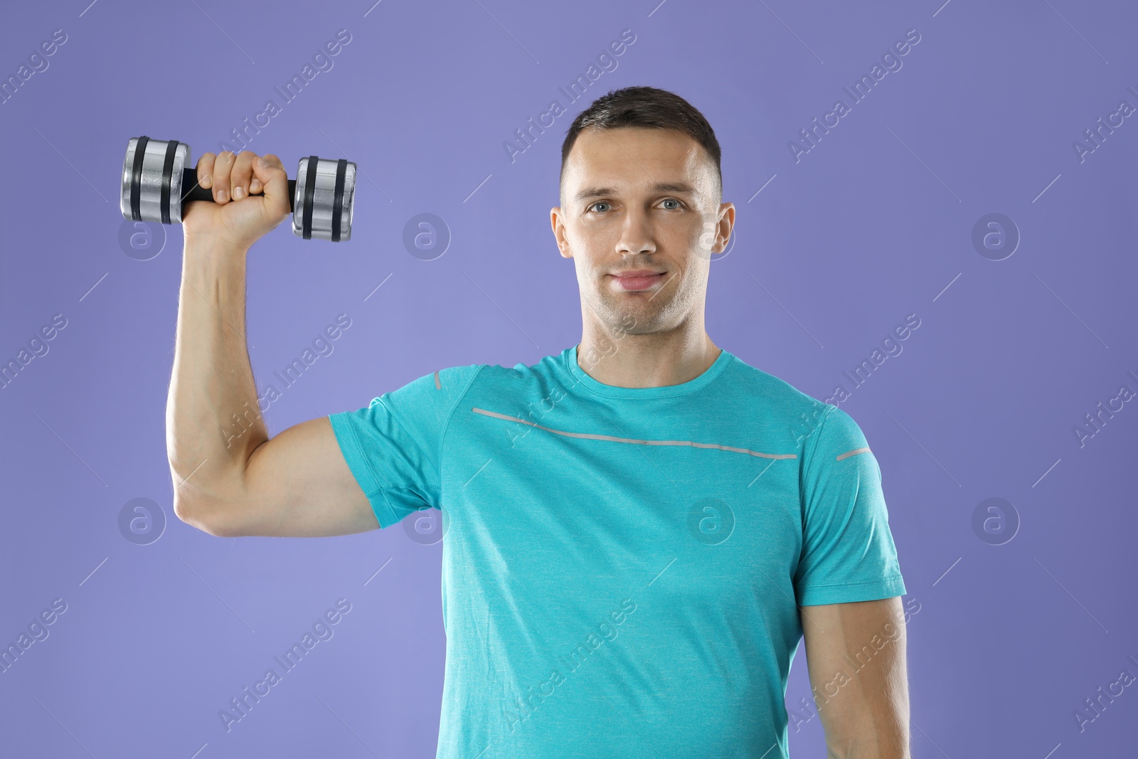 Photo of Man exercising with dumbbell on violet background