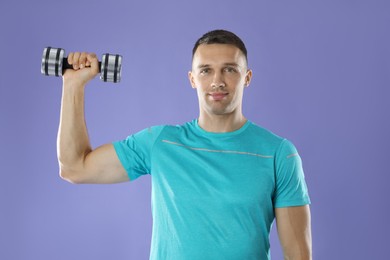 Photo of Man exercising with dumbbell on violet background