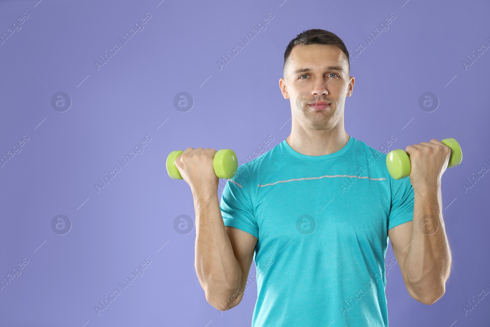 Photo of Man exercising with dumbbells on violet background, space for text