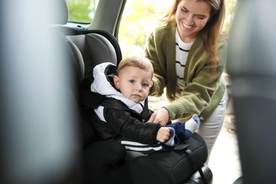 Photo of Smiling mother fastening her baby in car seat