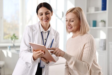 Doctor with tablet consulting woman in clinic