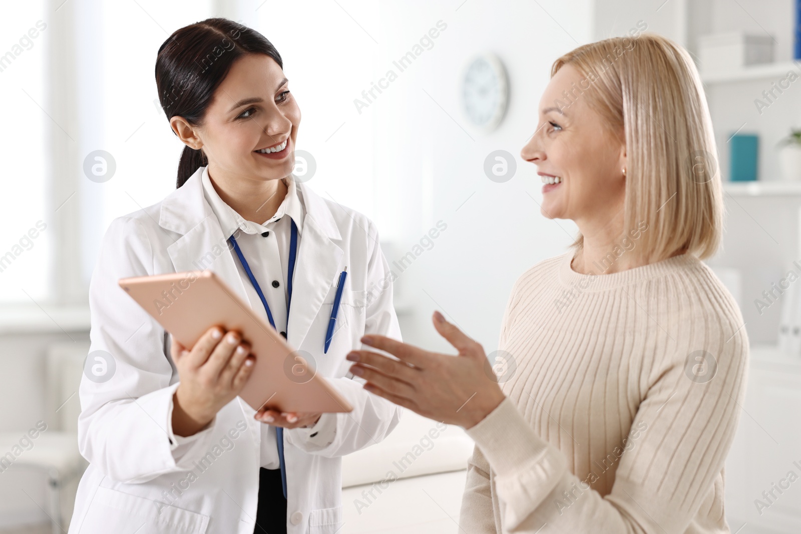 Photo of Doctor with tablet consulting woman in clinic