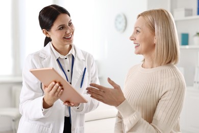 Photo of Doctor with tablet consulting woman in clinic