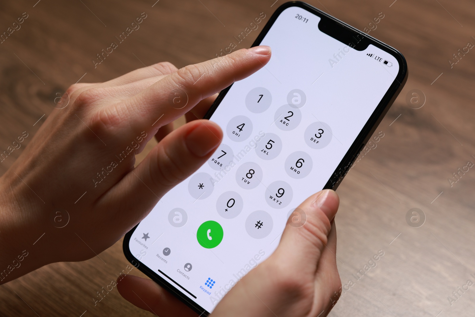 Photo of Woman dialing number on smartphone at wooden table, closeup