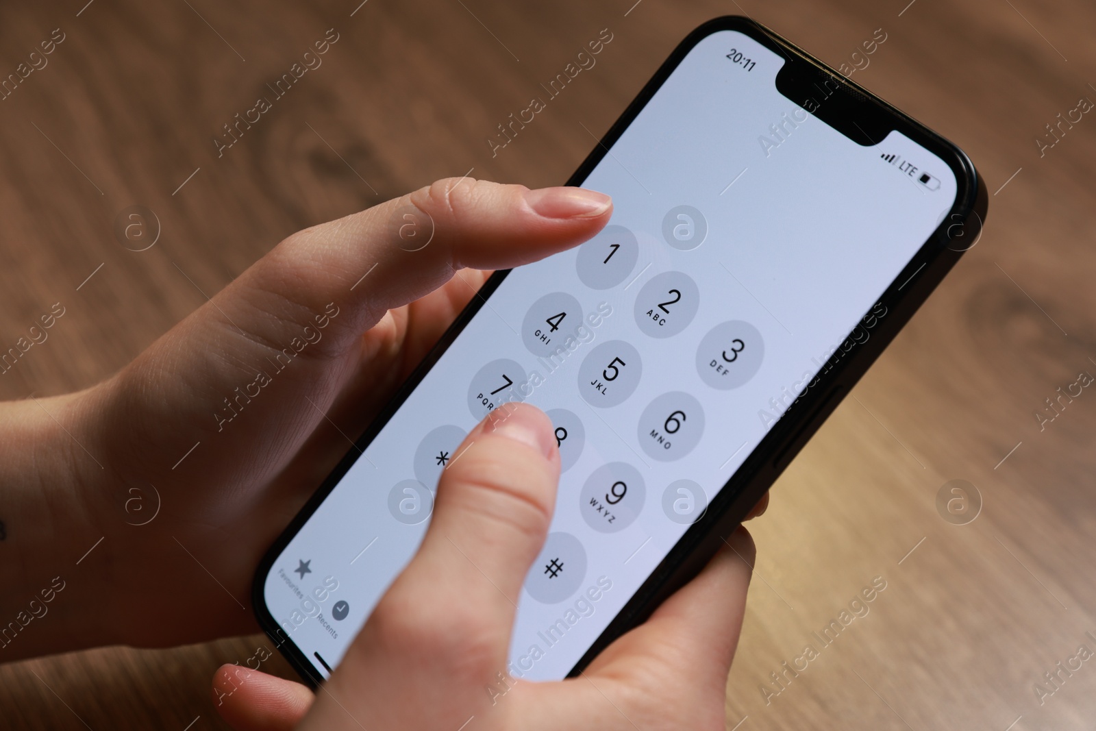 Photo of Woman dialing number on smartphone at wooden table, closeup