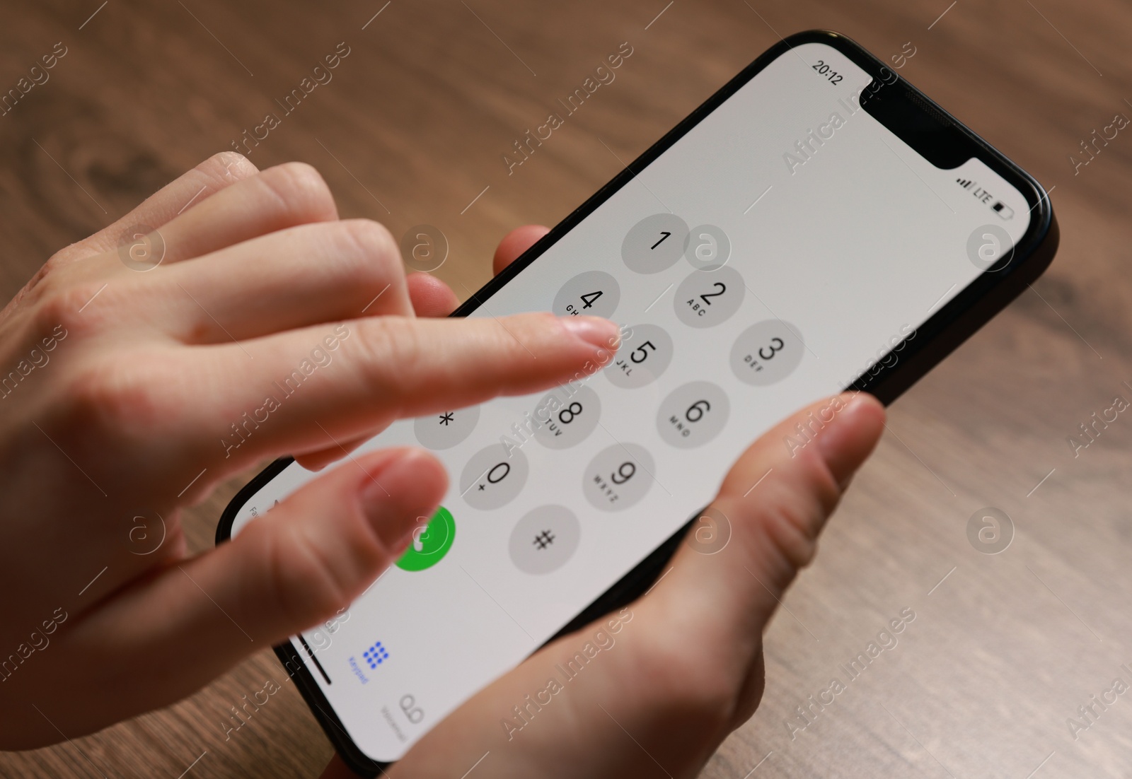 Photo of Woman dialing number on smartphone at wooden table, closeup