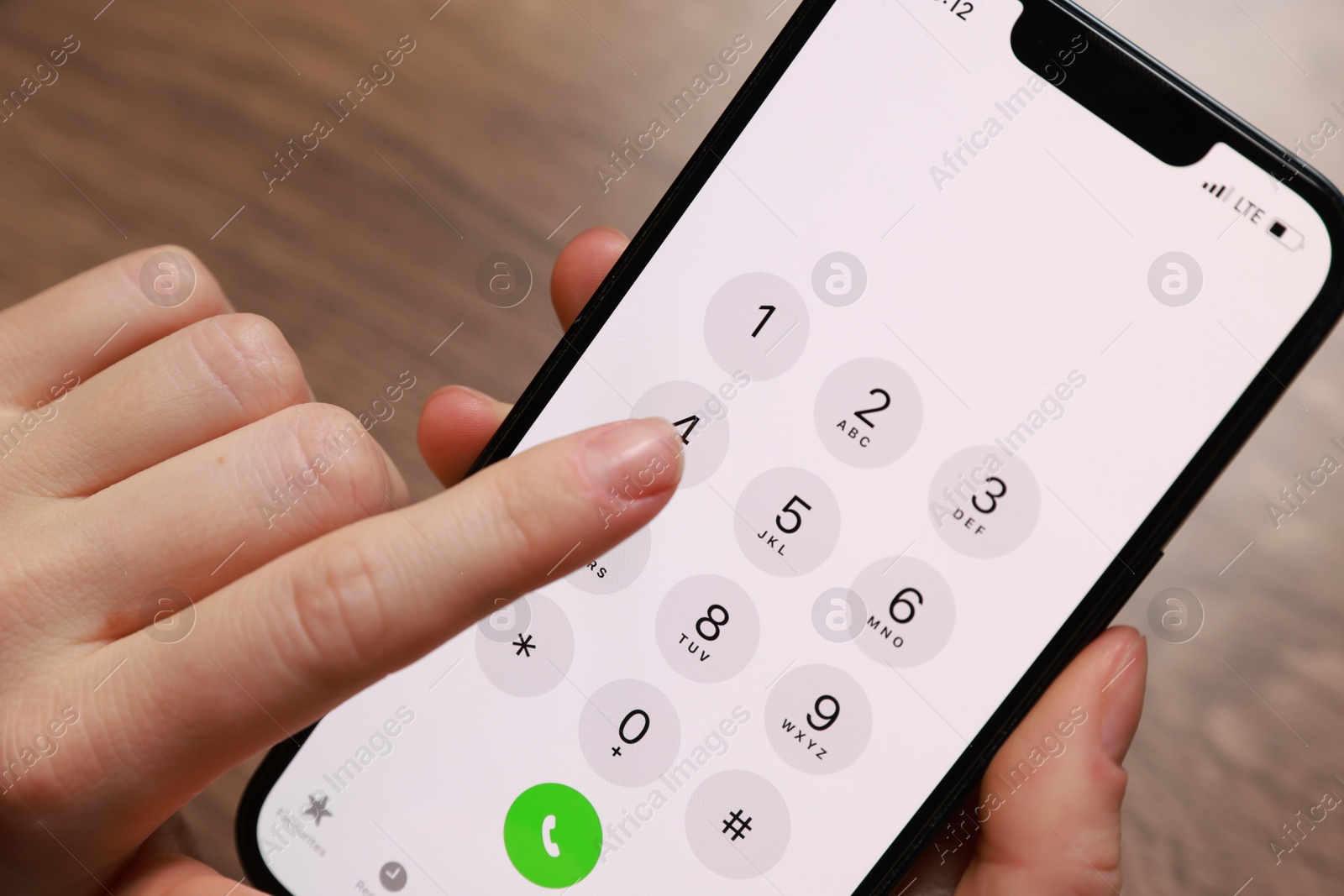 Photo of Woman dialing number on smartphone at wooden table, closeup