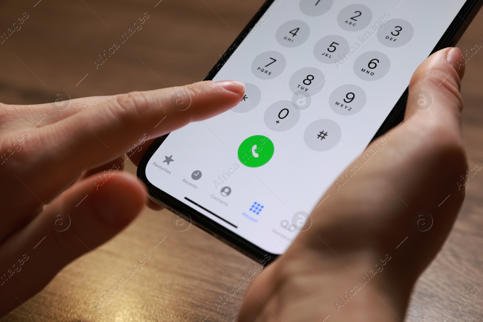 Photo of Woman dialing number on smartphone at wooden table, closeup