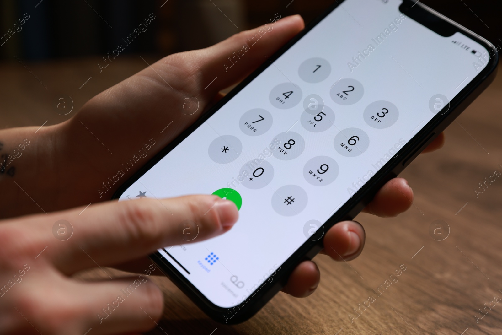 Photo of Woman dialing number on smartphone at wooden table, closeup