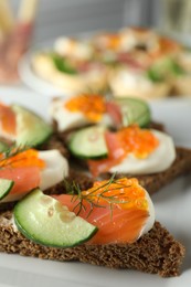 Photo of Tasty canapes with salmon and cucumber on plate, closeup