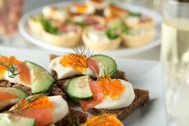 Photo of Tasty canapes with salmon and cucumber on plate, closeup