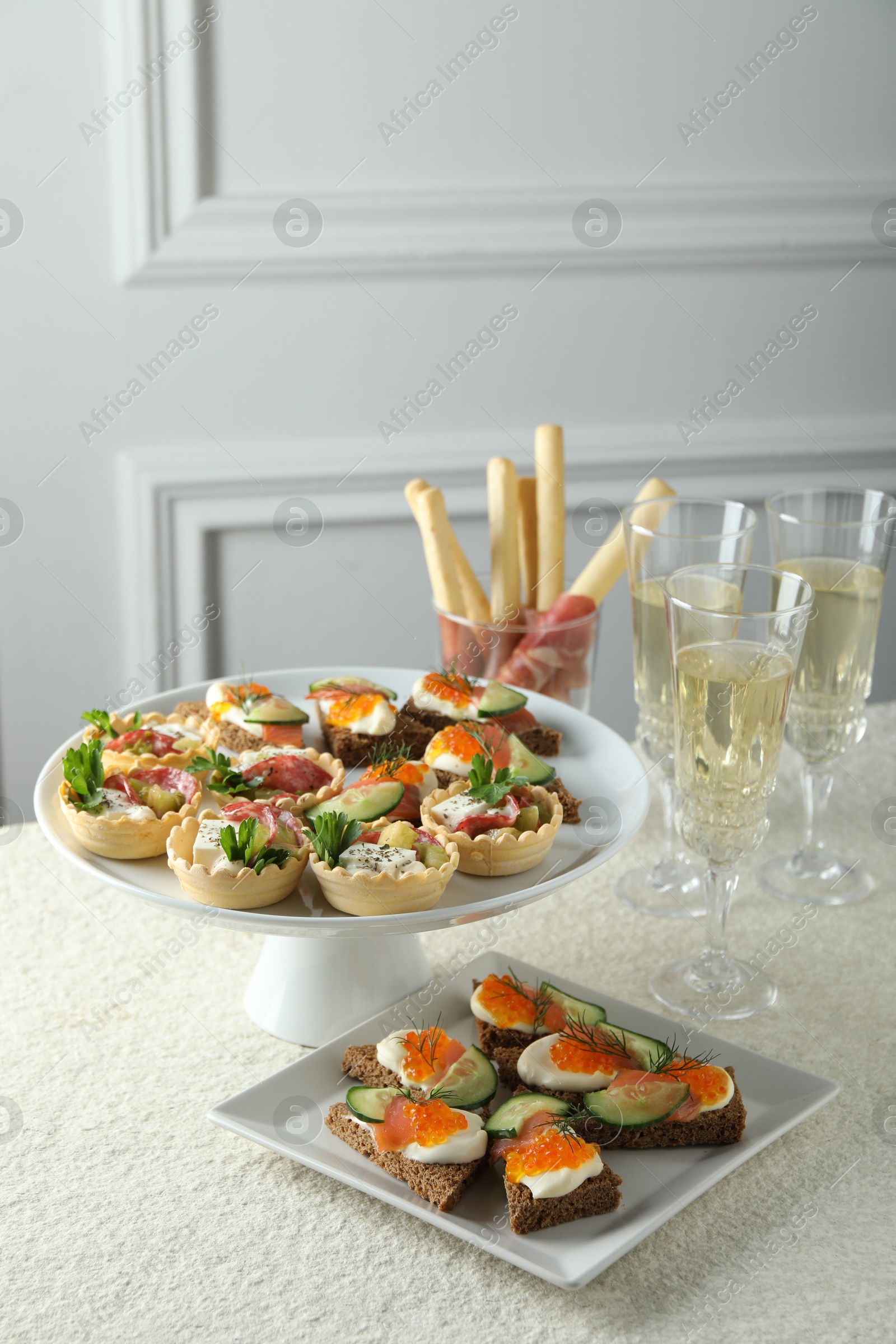 Photo of Many different tasty canapes and wine on white table