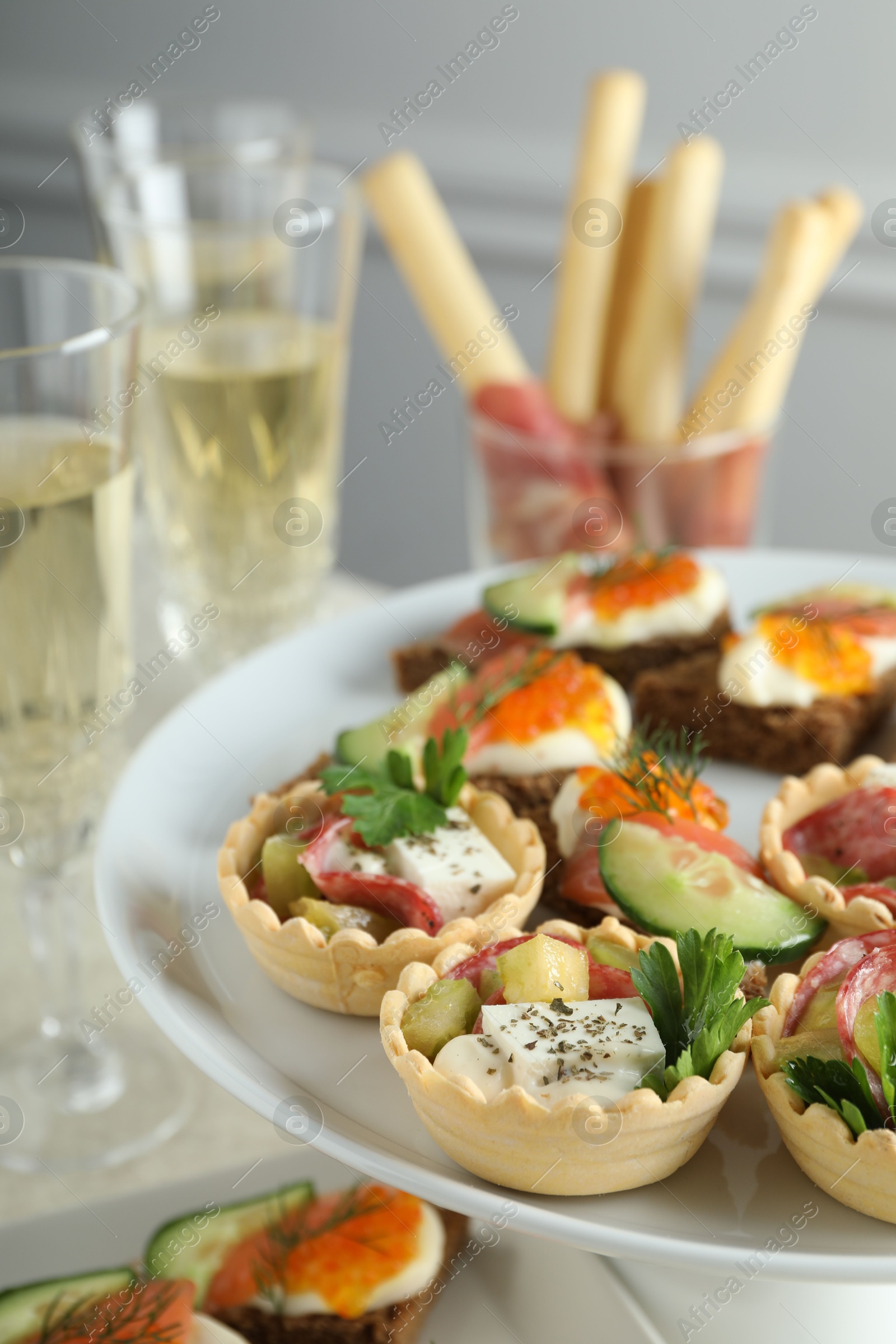 Photo of Many different tasty canapes and wine on white table, closeup