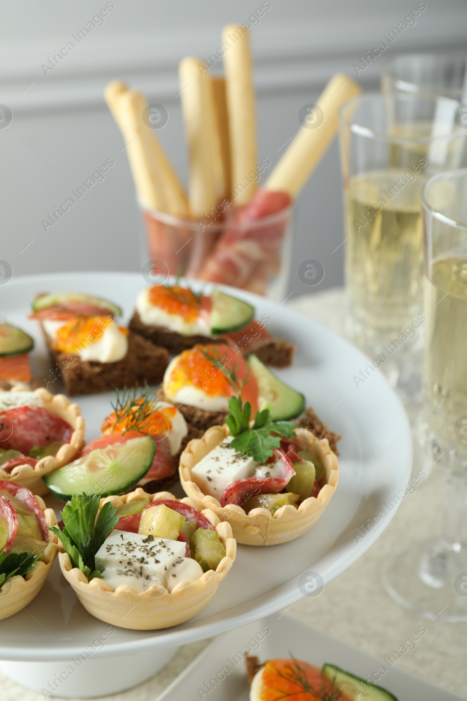 Photo of Many different tasty canapes and wine on white table, closeup