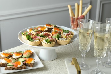 Photo of Many different tasty canapes and wine on white table