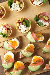 Photo of Many different tasty canapes on wooden table, flat lay