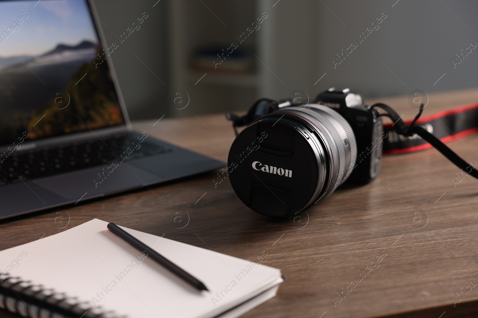 Photo of Professional photo camera, laptop and notepad on wooden desk indoors