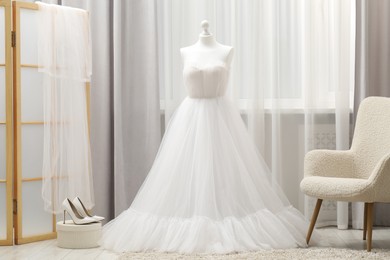 Photo of Beautiful wedding dress on mannequin and shoes in boutique