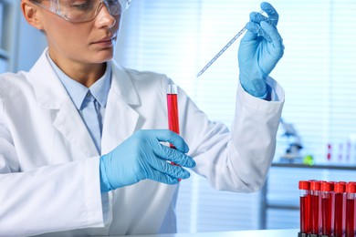 Photo of Laboratory testing. Doctor with blood sample and pipette indoors, closeup