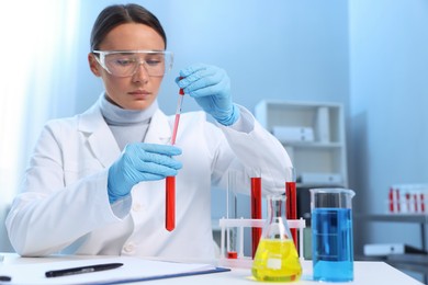 Laboratory testing. Doctor dripping blood sample into test tube at table indoors