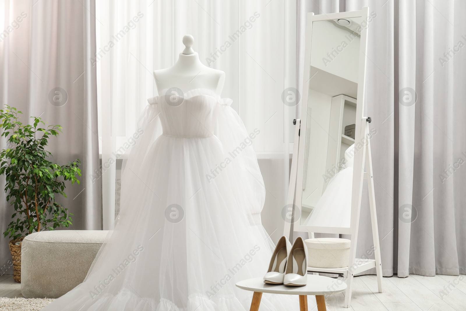 Photo of Beautiful wedding dress on mannequin and shoes in boutique