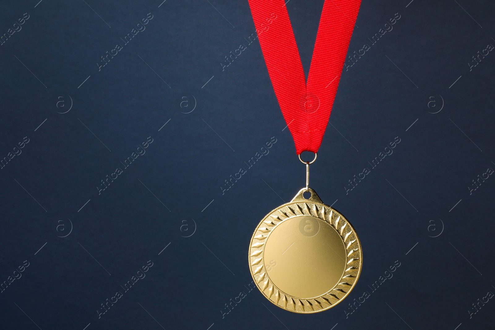 Photo of Golden medal with red ribbon on dark grey background, space for text