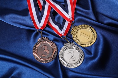 Photo of Golden, silver and bronze medals on blue fabric, above view