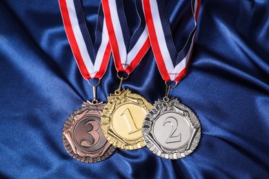 Photo of Golden, silver and bronze medals on blue fabric, above view