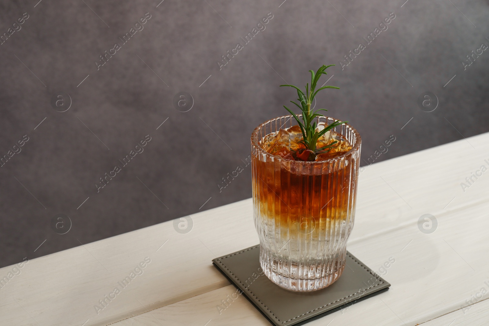 Photo of Refreshing espresso tonic drink with rosemary on white wooden table, space for text