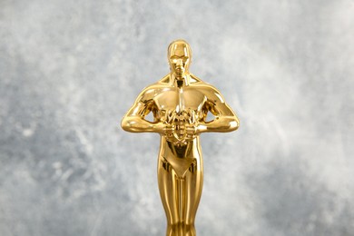 Photo of Golden trophy in shape of human figure against blurred gray background