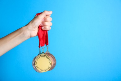 Photo of Woman with different medals on light blue background, closeup. Space for text