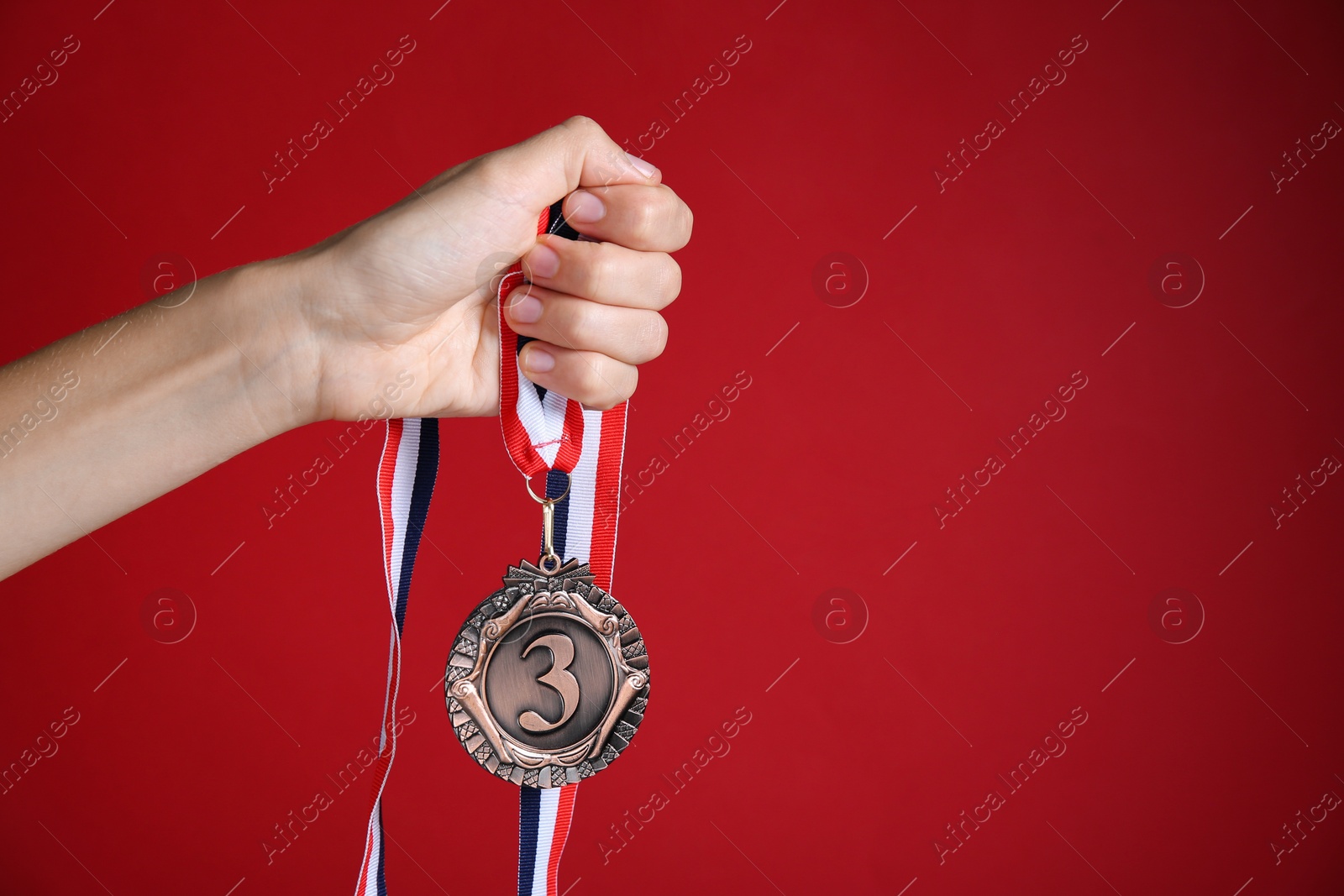 Photo of Woman with bronze medal on red background, closeup. Space for text