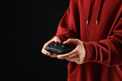 Photo of Teenage boy playing video game with controller on black background, closeup. Space for text