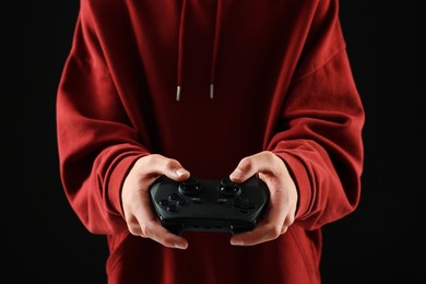 Photo of Teenage boy playing video game with controller on black background, closeup