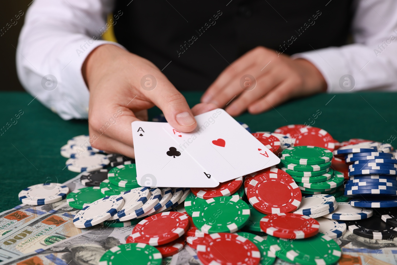 Photo of Professional croupier with playing cards at gambling table, closeup