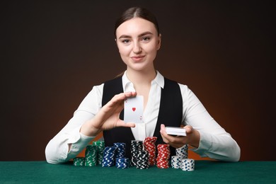 Professional croupier with casino chips and playing cards at gambling table on color background