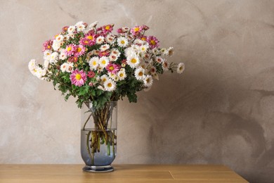 Photo of Vase with beautiful flowers on pink wooden table. Space for text