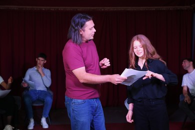 Photo of Professional actors with their scripts rehearsing in theatre