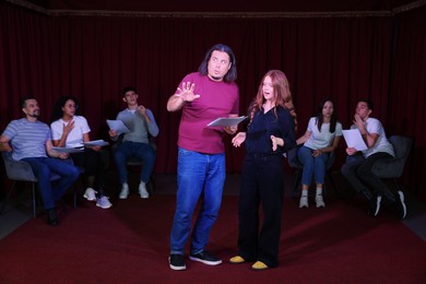 Professional actors with their scripts rehearsing in theatre