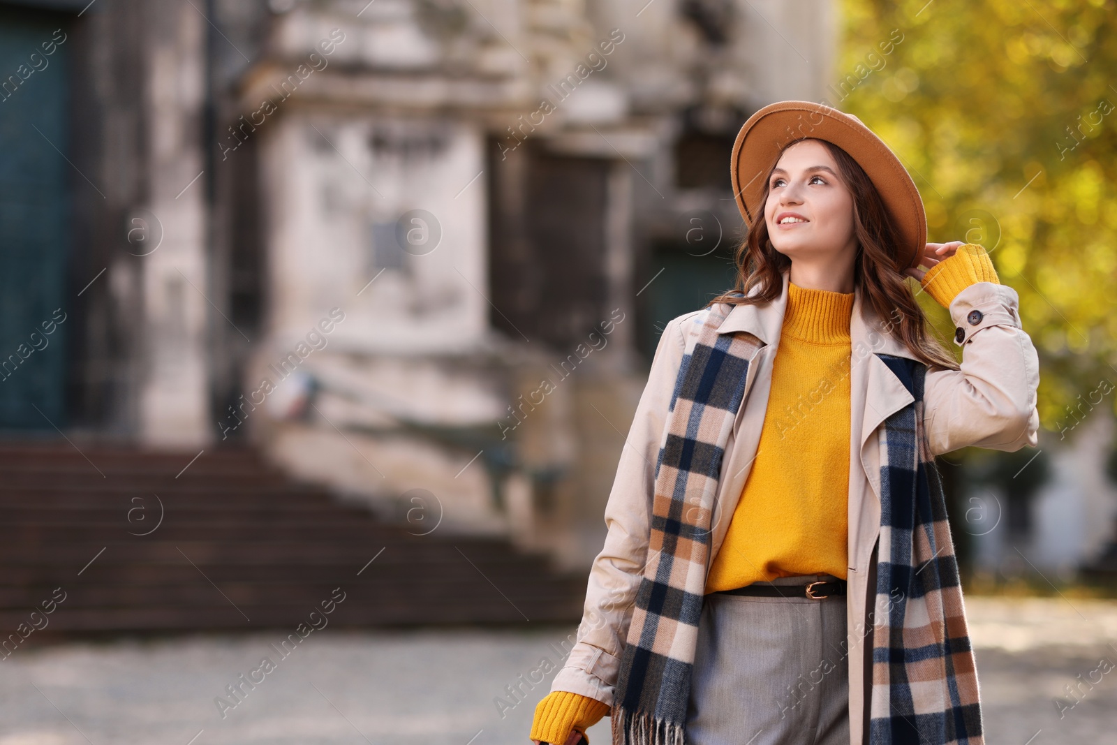 Photo of Charming young woman in stylish outfit on city street, space for text. Autumn season