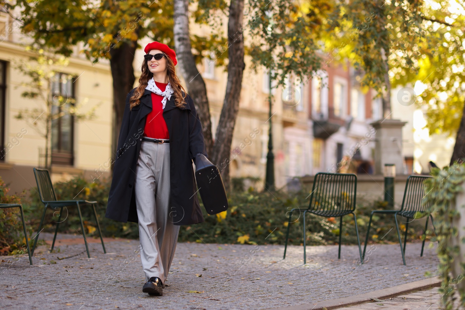 Photo of Charming young woman in stylish outfit on city street, space for text. Autumn season