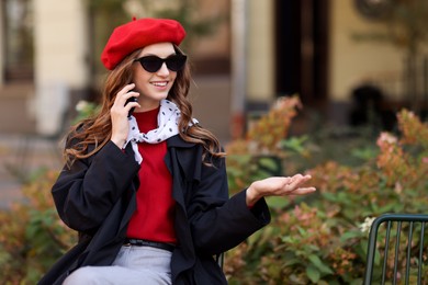 Photo of Stylish young woman talking on phone outdoors