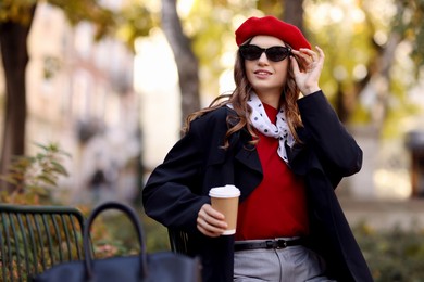 Photo of Stylish woman with cup of hot drink outdoors