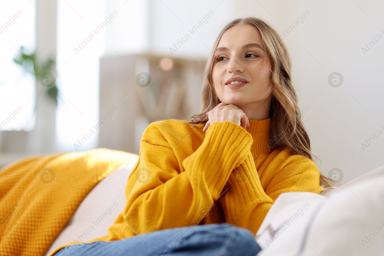 Photo of Charming young woman on sofa at home. Autumn atmosphere